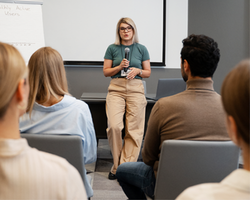 Female presenter facing audience of other professionals 