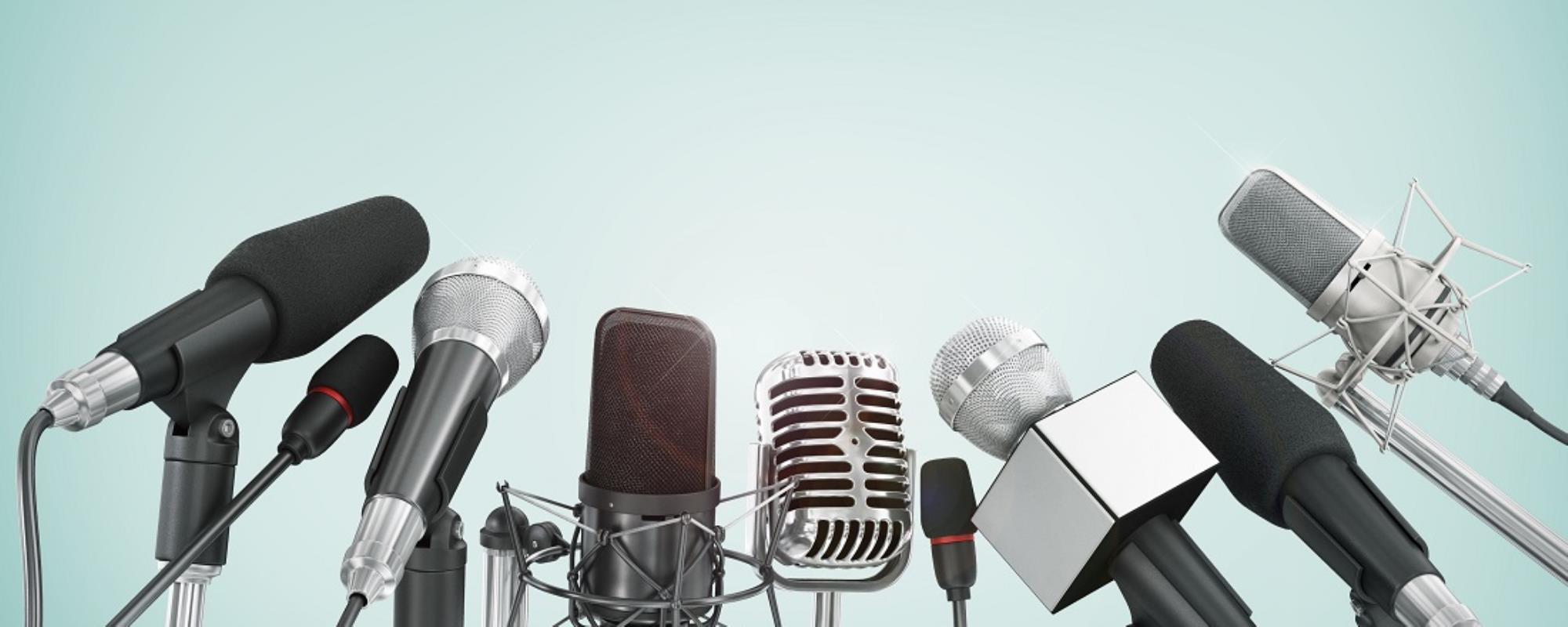 Seven microphones in a slight arch infront of a teal gradient backdrop