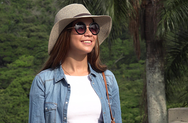 teen female wearing sun hat and sunglasses in a tropical setting