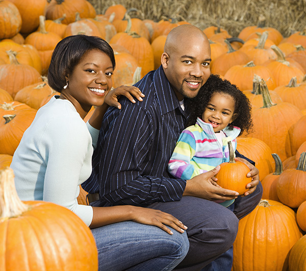 family of three posing in a pumpkin patch