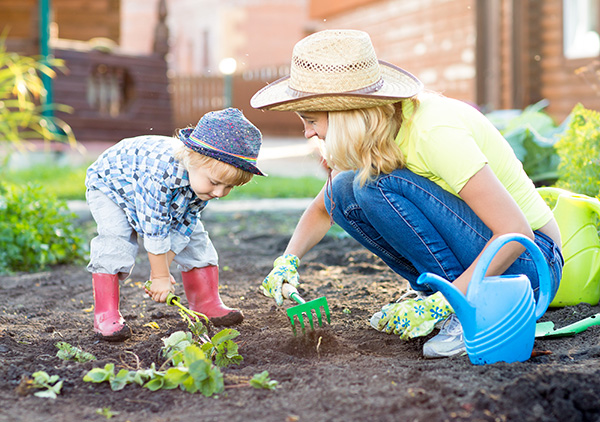woman and young child working soil with a small handheld rake in a home garden