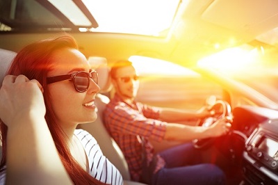 man and woman driving in car at sunset with sunroof open 