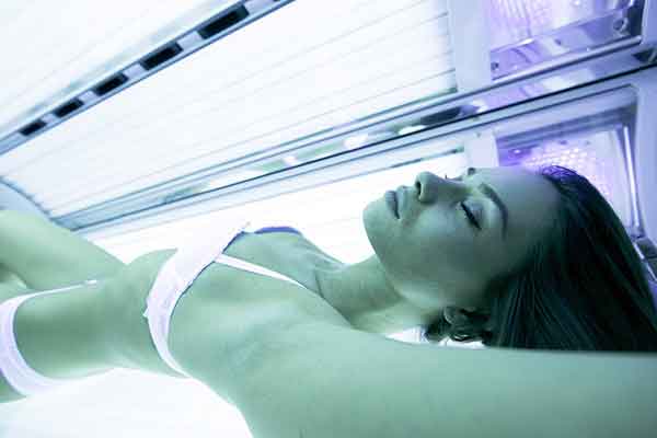 woman with eyes closed inside of a tanning bed