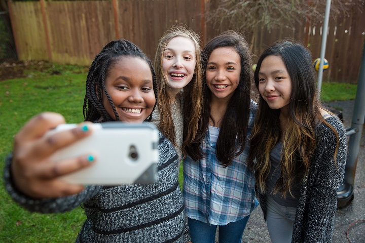 group of diverse teenage girls taking a selfie in a fenced in back yard
