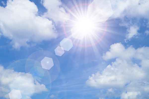 sun with sun flares and white clouds in a blue sky