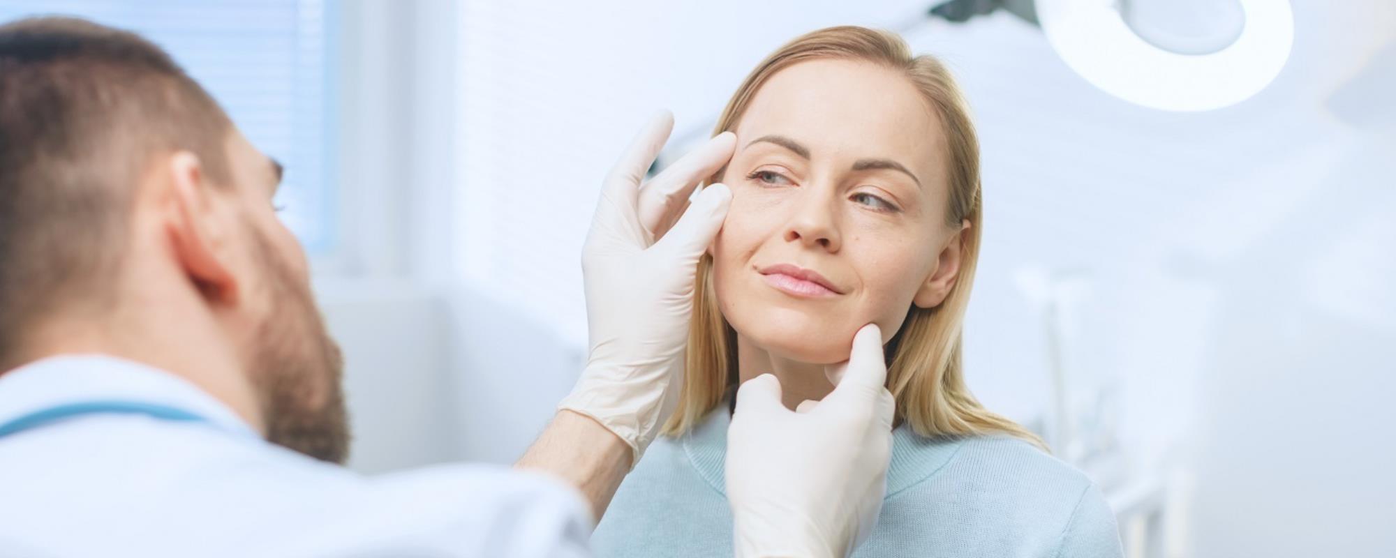 Female patient having face checked for skin conditions by a medical professional